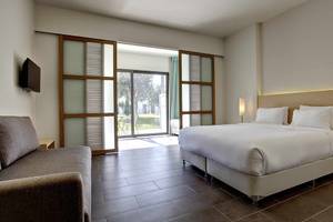 Innenansicht eines Zimmers im Club Plimmiri Hotel mit Doppelbett, Sofa, Tisch und modernem Design.