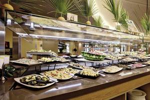 Buffet-Tisch im Club Plimmiri Hotel mit vielen verschiedenen Gerichten auf weißen Tellern.