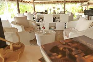 Loungebereich im Outrigger Maldives Maafushivaru Resort mit weißen Möbeln und Büchern.