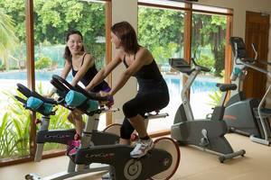 Zwei Frauen trainieren auf Fahrradtrainern im Fitnessstudio des Kurumba Maldives.