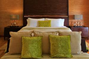 Schlafzimmer im Kurumba Maldives Hotel mit Bett, Kissen und Lampen.