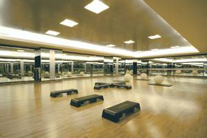 Innenansicht des Fitnessstudios im Pathumwan Princess Hotel mit Holzboden und Spiegelwänden.