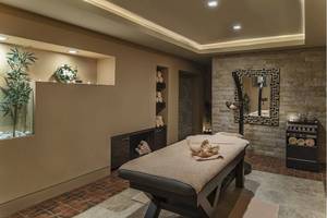 Spa-Behandlungsraum im Voyage Torba Hotel mit Massagetisch, gerollten Handtüchern, und dekorativen Elementen.