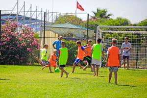 Kinder spielen Fußball auf einem Feld im Freien im Selectum Family Comfort Side Hotel.