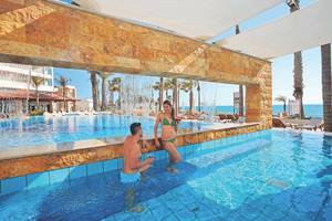 Ein Mann und eine Frau genießen den Pool im Alexander The Great Hotel.