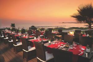 Alexander The Great Hotel Terrasse mit eingerichteten Tischen und Blick auf den Ozean bei Sonnenuntergang