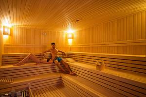 Paar in der Sauna im Terrace Elite Resort, entspannt auf Holzbänken sitzend.