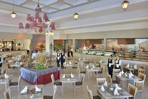 Innenansicht des Restaurants im Paradisus Princesa del Mar Resort & Spa mit gedeckten Tischen, Kellnern und einer großen Kristallleuchte.