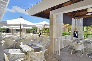 Außenbereich des Paradisus Princesa del Mar Resort & Spa mit weißen Stühlen, Tischen und Sonnenschirmen.