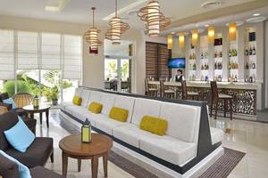 Loungebereich im Paradisus Princesa del Mar Resort & Spa mit einer gepolsterten Bank, Stühlen und einem Barbereich.