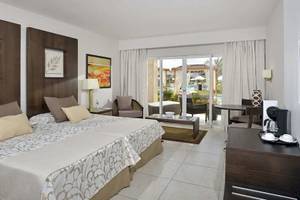 Hotelzimmer im Paradisus Princesa del Mar Resort & Spa mit Doppelbett, Wohnzimmerbereich und Terrassentür.