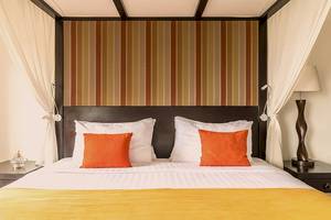 Bett im Jetwing Sea Hotel mit orangen Kissen und gestreiften Kopfteil.