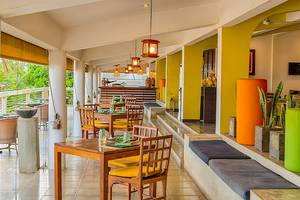 Innenansicht des Restaurants Jetwing Sea mit holzigen Tischen und Stühlen, gelben Wänden und Pflanzen.