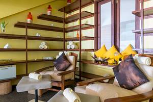 Innenansicht des Massageraums im Jetwing Sea Hotel mit Holzmöbeln, Kissen und Regalen mit Pflegeprodukten.