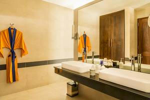 Badezimmer im Jetwing Sea Hotel mit zwei Waschbecken, Spiegel und gelben Kimonos