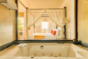 Badezimmer des Jetwing Sea Hotels mit Badewanne und Blick auf ein Bett mit Baldachin.