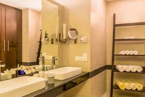 Badezimmer des Jetwing Sea Hotels mit zwei Waschbecken, Spiegel und Regal mit Handtüchern.