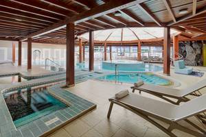 Innenpool des H10 Conquistador Hotels mit mehreren Becken und Liegestühlen.