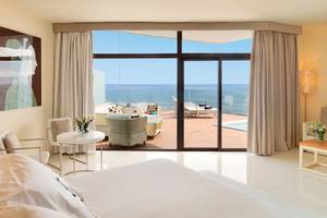 Suite im H10 Conquistador mit Meerblick, großem Bett und Terrassenmöbeln.