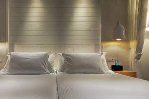 Doppelbettzimmer im H10 Conquistador Hotel mit weißen Laken, Kissen und Lampen.