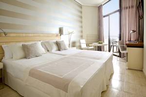 Doppelbett-Zimmer im H10 Conquistador Hotel mit gestreiften Wänden und Blick auf den Ozean.