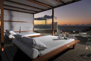 Terrasse des H10 Conquistador Hotels mit Betten, Kerzen und Meerblick.