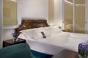 Doppelbett-Zimmer im H10 Conquistador Hotel mit weißen Laken, Kissen und Blumenvasen.