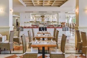 Innenansicht des Restaurants im H10 Conquistador Hotel mit Tisch, Stühlen und Buffet.