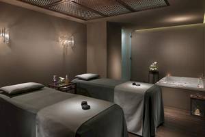 Spa-Behandlungsraum im H10 Conquistador Hotel mit zwei Massageliegen und einer Badewanne.