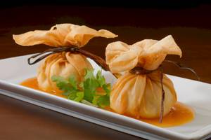 Zwei asiatische Gerichte auf einem weißen Teller mit Sauce und Gewürzen.