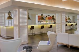 Lobby Bar des H10 Conquistador Hotels mit weißen Möbeln und Theke.