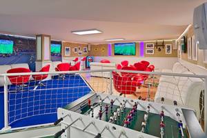 Spielzimmer im H10 Conquistador Hotel mit Tischfußball, roten Stühlen und Fernsehern