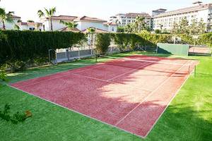 Tennisplatz des Paloma Oceana Hotels mit rotem Hartplatz und umlaufendem Rasen.