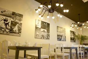 Innenansicht des Restaurants im Paloma Oceana Hotel mit weißen Tischen und Stühlen, Wandkunst und Kronleuchtern.