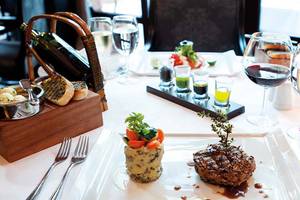 Gedecker Tisch im Paloma Oceana Hotel mit einem Gericht, Getränken und Zubehör.