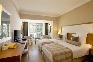 Doppelzimmer im Paloma Oceana Hotel mit zwei Betten, Fernseher, Schreibtisch und Balkon.