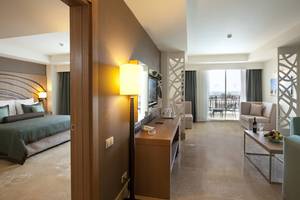Innenansicht eines Paloma Oceana Hotelzimmers mit Bett, Wohnzimmer und Balkon