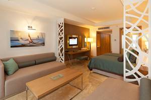 Innenansicht einer Suite im Paloma Oceana Hotel mit Wohnzimmer und Schlafzimmerbereich.