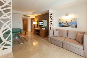 Wohnbereich im Paloma Oceana Hotel mit Sofa, Couch, Tisch, Fernseher und Gemälde.
