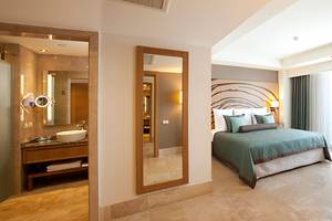 Innenansicht eines Schlafzimmers im Paloma Oceana Hotel mit Bett, Spiegel und Waschtisch.