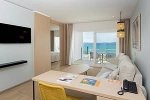 HSM Golden Playa Hotel Zimmer mit Meerblick, Fernseher, Schreibtisch, Sessel und Balkon mit Tisch und Stühlen.