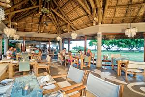 Innenansicht des Restaurants des Tamassa Bel Ombre Hotels mit Gästen, die an Tischen sitzen.