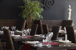 Innenansicht des Restaurants im Porto Bello Royal Hotel mit gedeckten Tischen und einer Statue.