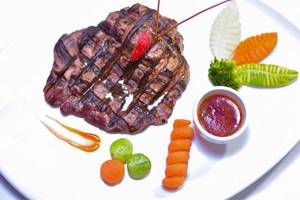 Gegrilltes Steak auf einem Teller mit Gemüse und Sauce.