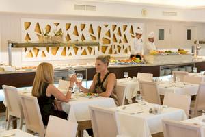Zwei Frauen in einem Restaurant des HSM Golden Playa Hotels, die Wein trinken und essen.