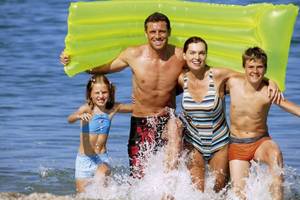Familie im Wasser mit einem gelben Schwimmbrett, Falkensteiner Club Funimation Garten Kalabrien