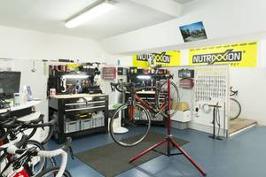 Ein Fahrrad-Reparaturbereich mit mehreren Fahrrädern, Werkzeugen und Bannern.