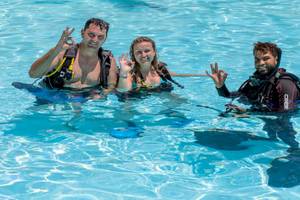 Drei Taucher im Schwimmbecken des Playabachata Spa Resort machen ein Friedenszeichen.