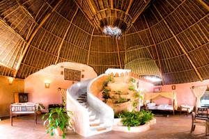 Innenansicht des Sands at Chale Island Resorts mit geschwungener Treppe und Pflanzen.
