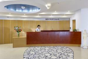 Receptionsbereich des Astir Beach Hotels auf Kreta mit Angestellter und Blumenvase.